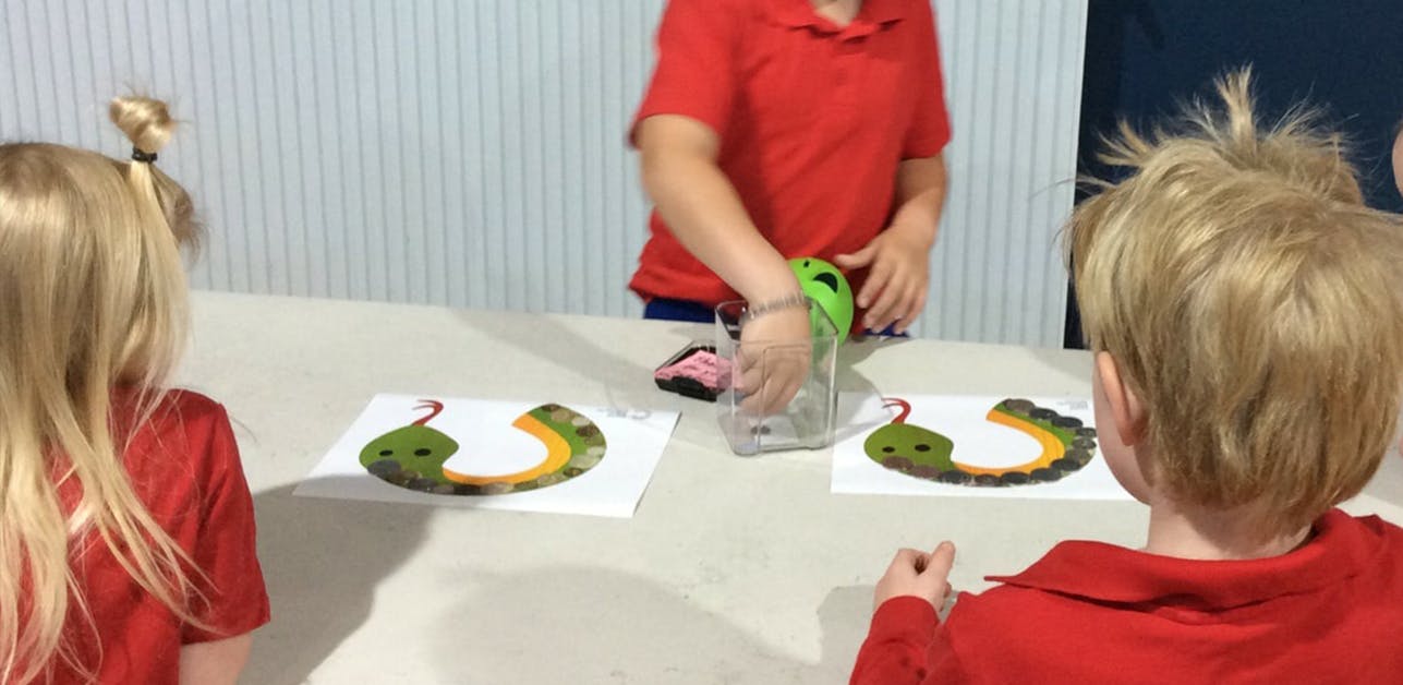 Three children participating in the coin snake activity.